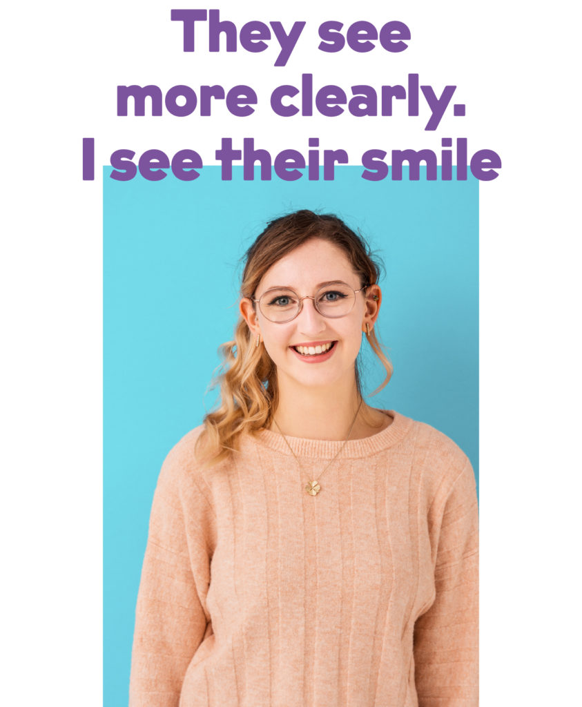 A picture of a girl with glasses and pink jumper standing in front of a blue background